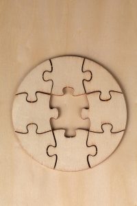 Round wooden puzzle with missing piece on a wooden background, top view.