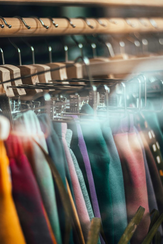 pexels-photo-14585221-14585221 Vibrant clothing lined up on hangers behind a glass window, showcasing a modern retail store.