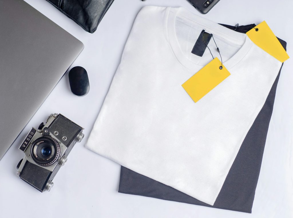 pexels-photo-14870714-14870714 Stylish flat lay featuring a vintage camera, clothing, and laptop on a clean white background.