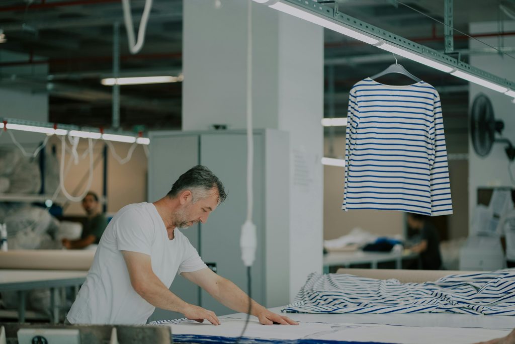 pexels-photo-13159722-13159722 Adult male in a textile workshop working with striped fabric indoors.
